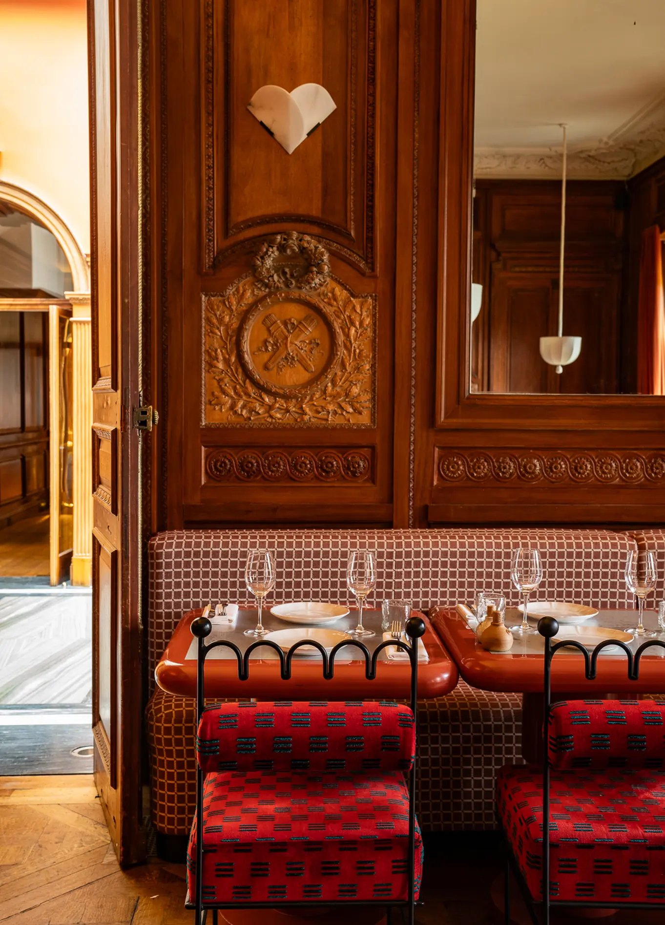 Elegant dining room with wooden panelling and red chairs at Cowley Manor restaurant, Cotswolds