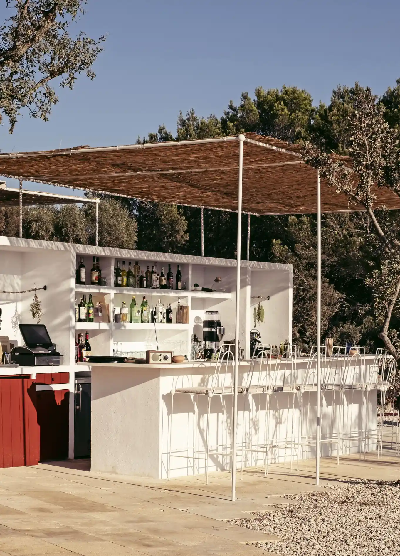 Modern and elegant outdoor beach bar, featuring a clean white structure under a wooden pergola, offering a relaxed atmosphere.