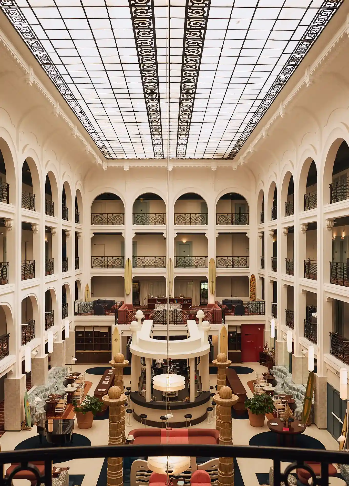 Panoramic view of the spectacular and bright atrium of the Regina Experimental hotel, featuring its classic arches and glass roof.