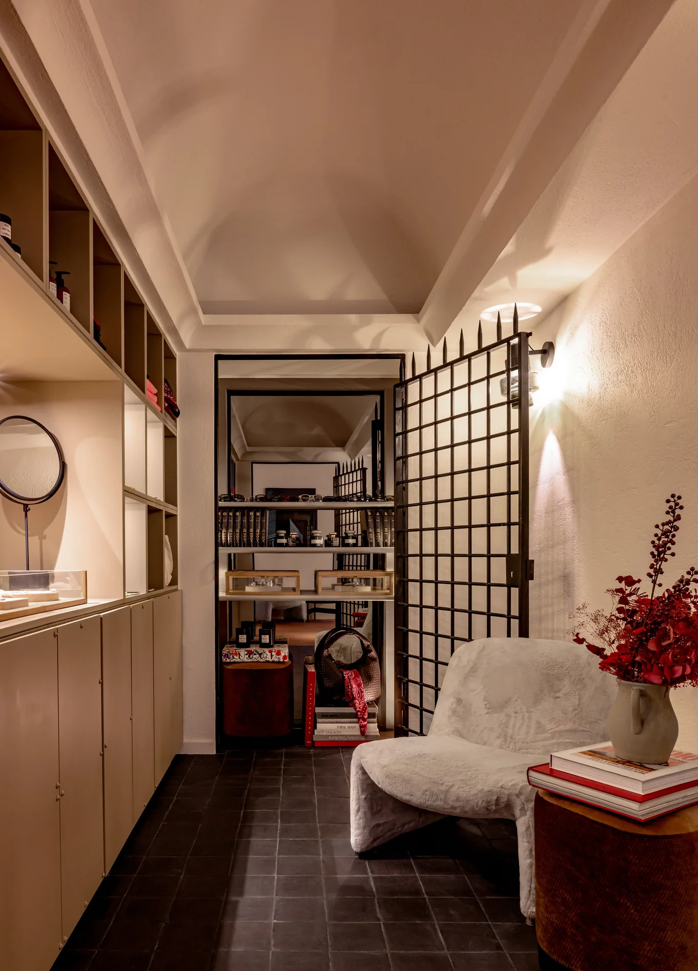 Boutique with warm lighting, wooden shelving, a fluffy armchair and a bouquet of red flowers at Experimental Marais, luxury boutique hotel in le Marais, Paris
